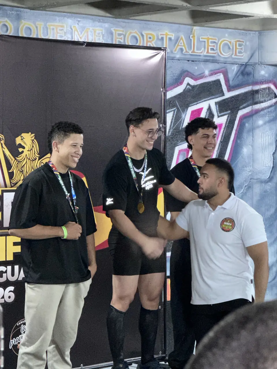 Premiación del qualifier de la World Raw Powerlifting Federation, con la bandera de la federación de fondo.